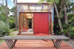 a bench sitting on top of a wooden deck in front of a red door and window