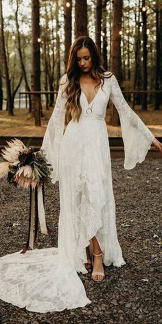 a woman in a white dress is standing on the ground with her arms outstretched and holding a bouquet