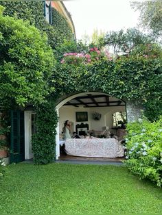 an outdoor living area with green plants on the walls, and a couch in the middle