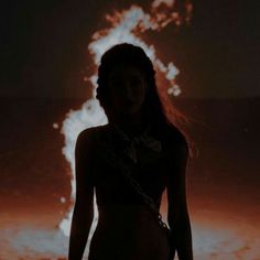 a woman standing in front of a fire with flames coming out of her chest and behind her back