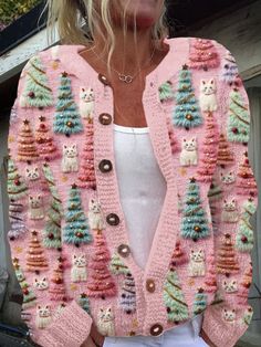 a woman wearing a pink cardigan sweater with cats and christmas trees on the front