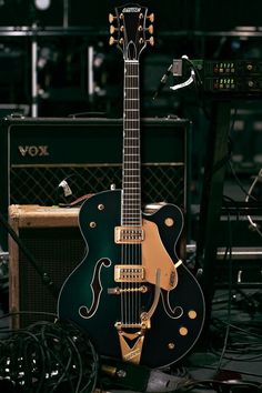 a black and gold guitar sitting on top of a table next to an ampl