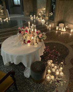 a table with candles and flowers on it in the middle of a room filled with chairs