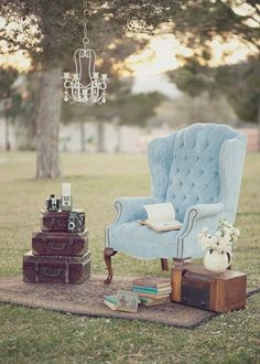 a blue chair sitting on top of a rug next to a table with luggage and a chandelier