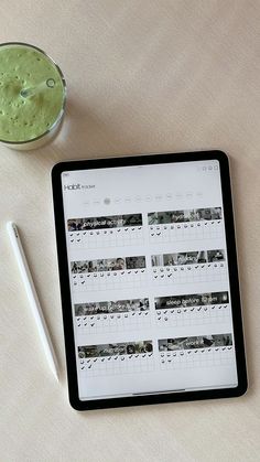 a tablet with a calendar on it next to a cup of green liquid and a pen