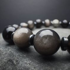 "Discover the harmonious blend of style and spiritual strength with our 8mm Silver Obsidian Stone Beaded Bracelet. Crafted for both men and women, this bracelet features genuine Silver Obsidian beads on a stretch cord, offering comfort and flexibility. The 925 Sterling Silver accents add an elegant touch to this protective accessory. Experience the grounding influence on the Root chakra, thanks to the powerful properties of Silver Obsidian. Ideal for those seeking a stylish protection bracelet, Obsidian Round Beads Jewelry 8mm, Polished Round Obsidian Bead Jewelry, Silver Obsidian, Spiritual Strength, Energy Balancing, Obsidian Stone, Hematite Bracelet, Protection Bracelet, Handmade Jewelry Gift