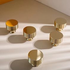 four brass knobs are arranged on a white surface