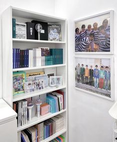 there are two pictures on the wall behind this bookcase, and one is displaying children's books