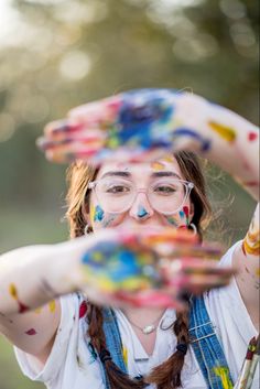 a woman with painted hands holding something up to her face