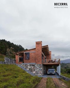 a car is parked in front of a brick house with a stone wall and roof