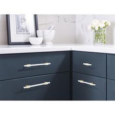 an image of a kitchen setting with blue cabinets and white counter tops, flowers in vase