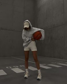 a woman holding a basketball while standing in an empty room