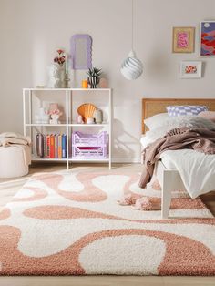 a bedroom with pink and white decor on the walls, rugs and bedding