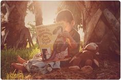 a person sitting on the ground with a sign and stuffed animals in front of them