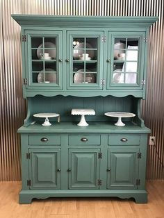 a green china cabinet with dishes on top