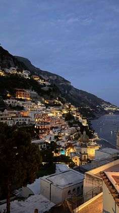 the city is lit up at night by the ocean