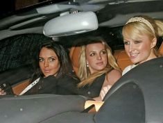 three women sitting in the back seat of a car