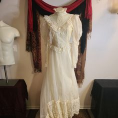 an old fashioned white dress hanging on a wall