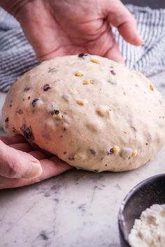 a person holding a doughnut in their hand on top of a marble countertop