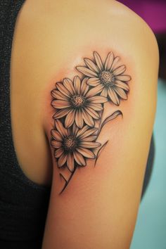 Tattoo of three daisy flowers on upper arm. Gerber Daisy Tattoos For Women, Daisy Shoulder Tattoos For Women, Rose And Daisy Tattoo, Daisy Tattoo Ideas, Women Small Tattoos, Chocolate Turtles