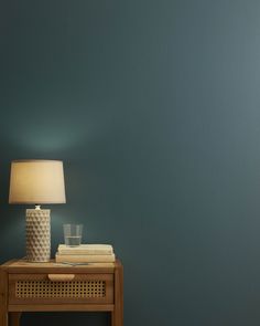 a table with a lamp on it next to a wall painted in teal green