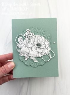 a hand holding up a card with flowers on the front and bottom, which is made out of green paper