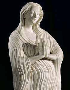 a white statue with long hair holding her hands together