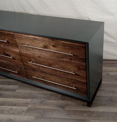 a black and wood dresser with metal handles