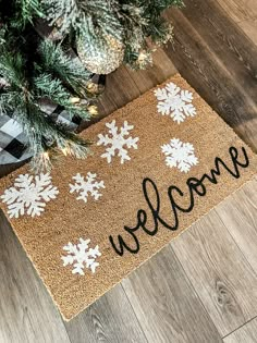 a welcome mat with snowflakes on it sitting next to a christmas tree in the living room