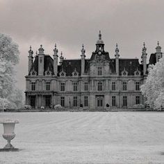 a large building with a clock on the top of it's tower and trees around it