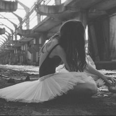 a woman sitting on the ground next to a horse wearing a tutu and dress