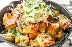 a skillet filled with potatoes covered in parmesan cheese