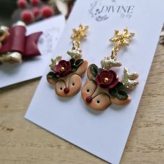 the earrings are decorated with red flowers and gold leaves on top of each earring