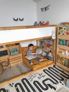 a young boy sitting on top of a bunk bed in a room filled with books