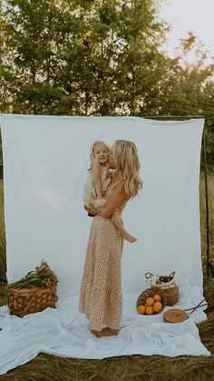 two women hugging each other in front of a white backdrop with oranges and apples