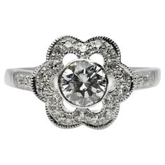 a white gold ring with an intricate flower design and round brilliant cut diamonds on the band