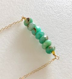 "Raw natural green chrysoprase rondelles wire wrapped with 24k gold vermeil accents in bar necklace. Natural raw faceted 7mm chrysoprase rondelles in shades of green and brown with little imperfections throughout are wire wrapped with 24k gold vermeil cubes. Gemstone bar is 1 3/4\" wide. Delicate cable chain with spring ring clasp is 14k gold fill. Also available in Sterling silver. This exact necklace has sold but yours will be from the same strand of gemstones and just as lovely!" Paris Charm Bracelet, Chrysoprase Necklace, Lapis Necklace, Rustic Boho, Custom Bracelets, Gemstone Healing, Chain Ring, Bar Necklace, Boho Necklace