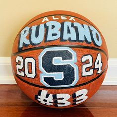 an orange and black basketball sitting on top of a wooden floor next to a wall