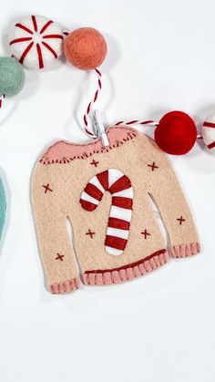 an ornament made to look like a sweater with candy canes hanging from it