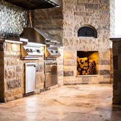 an outdoor kitchen with stone walls and grill