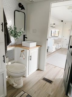 a white toilet sitting inside of a bathroom next to a wooden counter top under a mirror