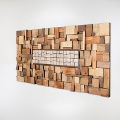 a piece of art made out of wooden blocks on a white wall with a window in the middle