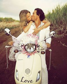 a man and woman kissing on the back of a scooter