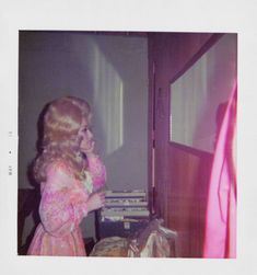 an old photo of a woman standing in front of a tv