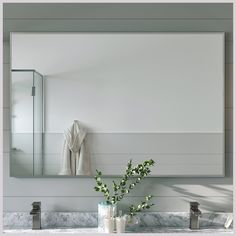 a bathroom with marble counter tops and white walls, along with a large mirror above the sink