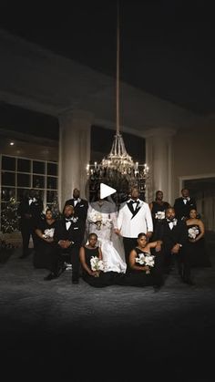 a bride and groom posing with their wedding party in front of a chandelier