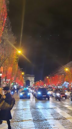 a city street filled with lots of traffic next to tall buildings and trees covered in christmas lights