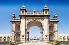 an ornate archway in the middle of a park with trees and flowers on either side