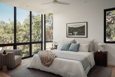 a large bed sitting next to two windows in a bedroom under a painting on the wall