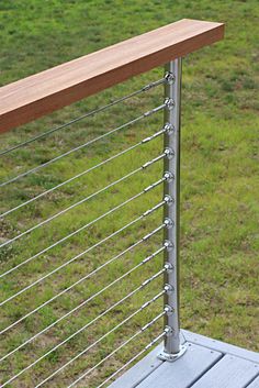 a close up of a metal and wood railing on a grassy field with trees in the background